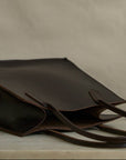 Brown leather tote bag on a neutral background